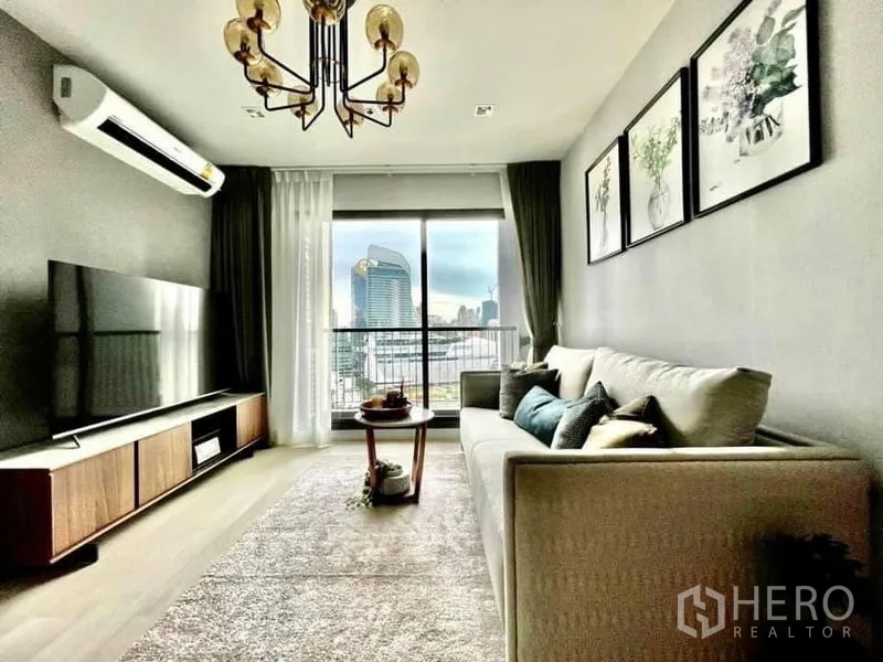 Condominium for rent in Pathum Wan, Bangkok - Living room facing TV and balcony, large windows framing the Bangkok skyline.