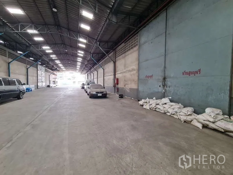 Warehouse for rent - Drive-through loading corridor with oversized sliding metal doors and parking bays.
