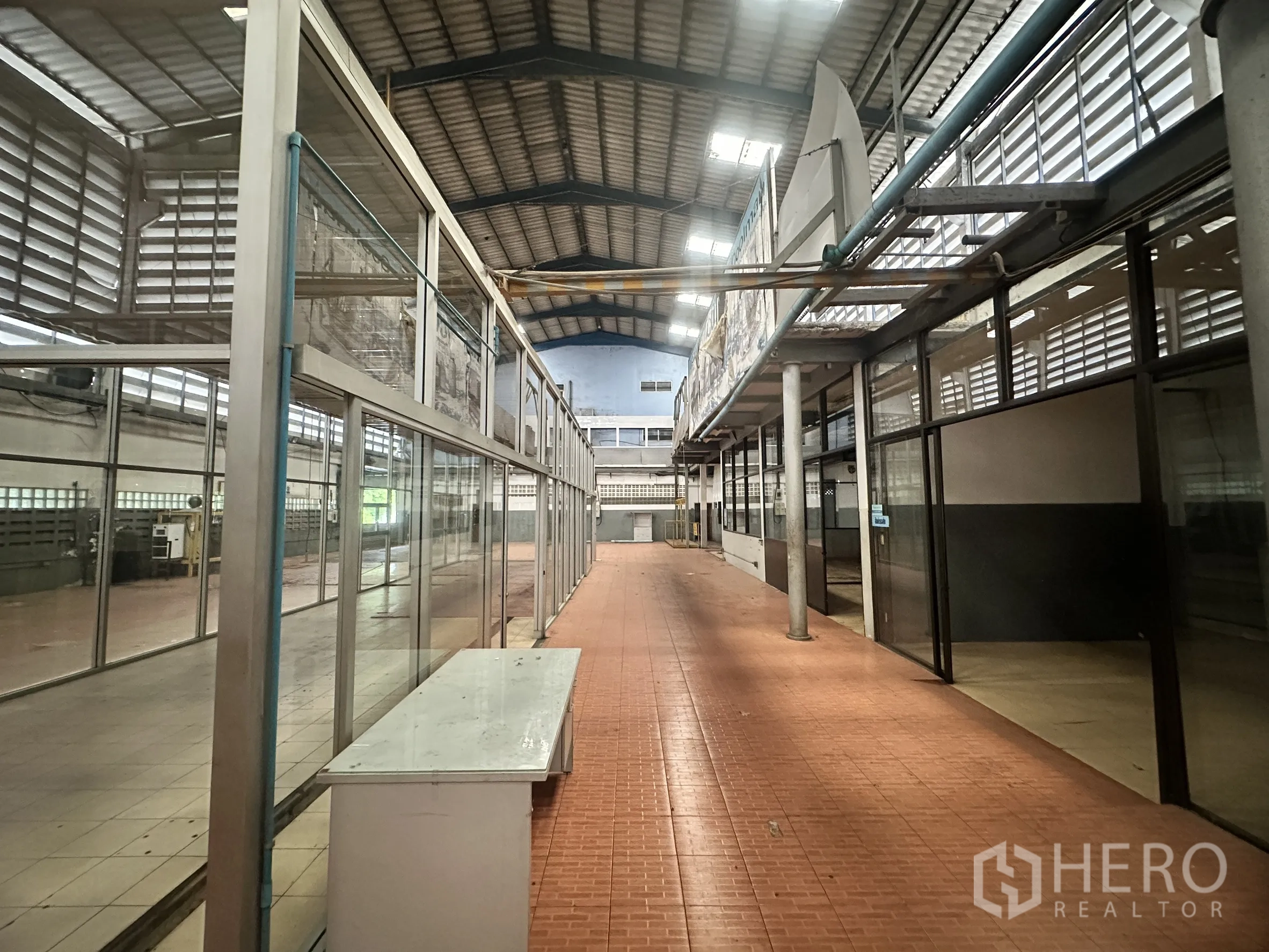 Factory for sale in Bang Bua Thong, Nonthaburi - Aisle inside the production area with glass-enclosed rooms and ventilated walls.
