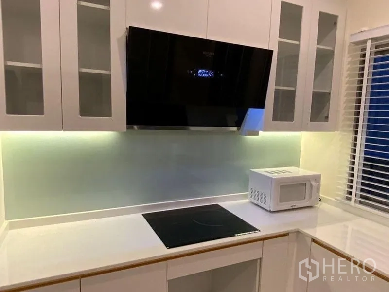 联排别墅 出租在Prawet, Bangkok - 厨房灶台、抽油烟机与背板灯光特写。