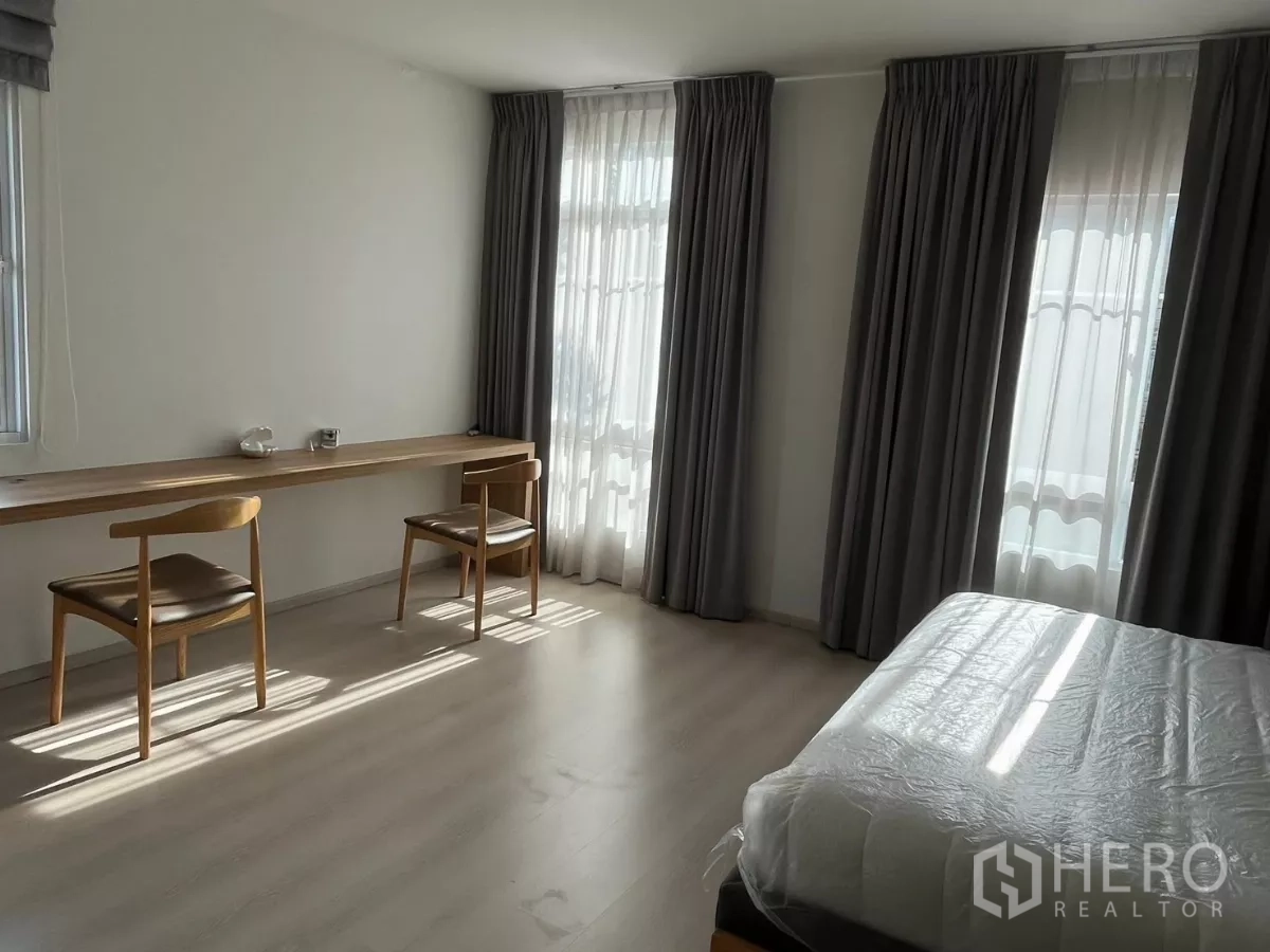 Townhouse for rent in Bang Phli, Samut Prakan - Primary bedroom with large windows, long work desk and two chairs.