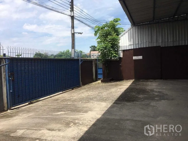 คลังสินค้า ให้เช่าในBueng Kum, Bangkok - ลานขนถ่ายสินค้ามีรั้ว ประตูสไลด์สีน้ำเงิน และหลังคากันฝนหน้าโกดัง