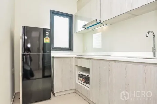 คอนโด ให้เช่าในDin Daeng, Bangkok - ครัวรูปตัวแอลสว่าง โทนไม้ลายอ่อน มีหน้าต่าง เครื่องดูดควัน และตู้เย็นสีดำ