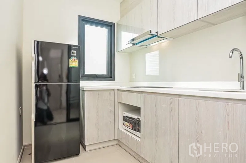 คอนโด ให้เช่าในDin Daeng, Bangkok - ครัวรูปตัวแอลสว่าง โทนไม้ลายอ่อน มีหน้าต่าง เครื่องดูดควัน และตู้เย็นสีดำ