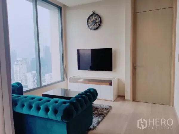 คอนโด ให้เช่าหรือขายในWatthana, Bangkok - ห้องนั่งเล่นโซฟากำมะหยี่สีเขียวติดทีวีผนัง พร้อมหน้าต่างวิวเมือง