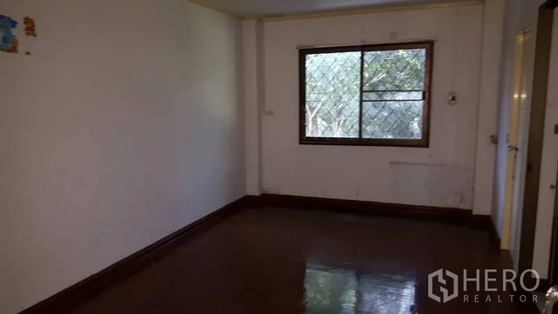 Detached House for rent in Khlong Toei, Bangkok - Upstairs bedroom with a window and glossy wood floor.