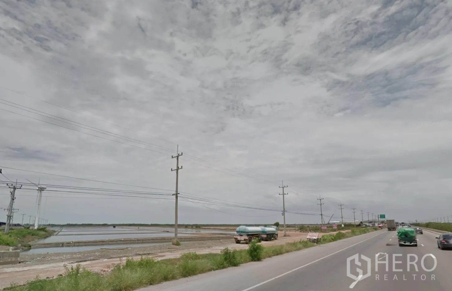 Land for sale in Mueang Samut Sakhon, Samut Sakhon - Multi-lane highway with roadside power poles and open flat land with water ponds.