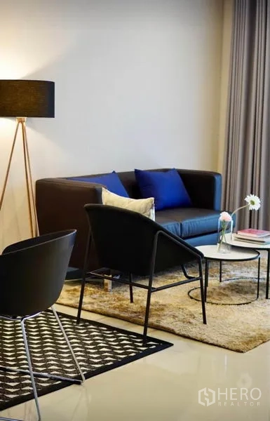 ทาวน์เฮาส์ ให้เช่าหรือขายในWang Thonglang, Bangkok - ห้องนั่งเล่นสไตล์โมเดิร์น โซฟาสีเข้ม โคมไฟตั้งพื้น และโต๊ะกลางบนพรม