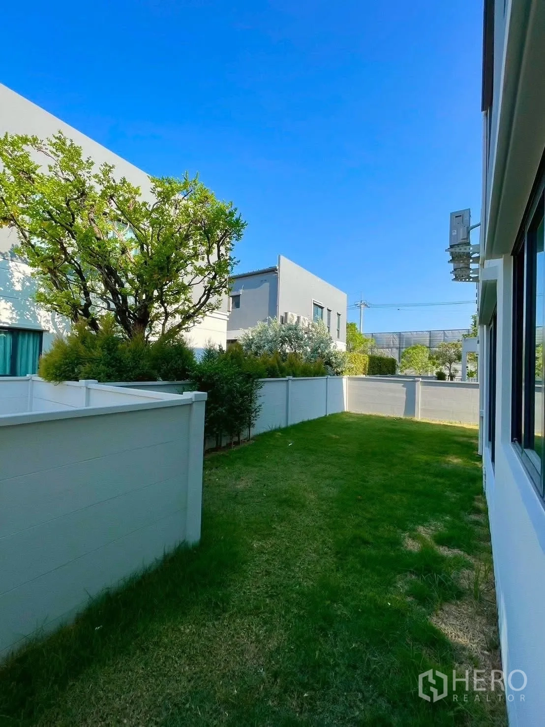 Detached House for rent in Bang Phli, Samut Prakan - Private side garden with lawn, white fence, and trees beside modern houses.