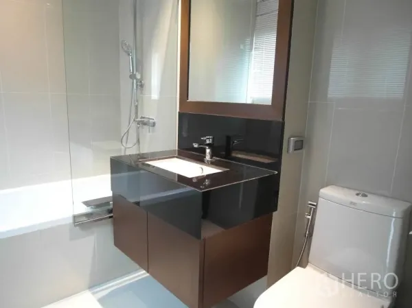 公寓 出租或出售在Sathon, Bangkok - 现代卫浴，带玻璃隔断浴缸、镜柜洗手台与坐便器。