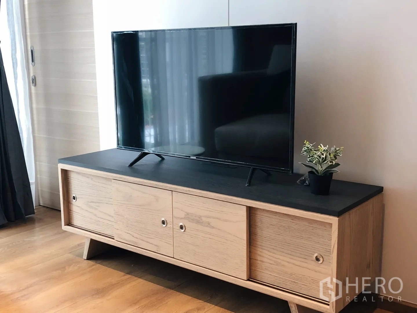 Condominium for rent in Khlong Toei, Bangkok - Flat-screen TV on a light wood media console with small plant decor.