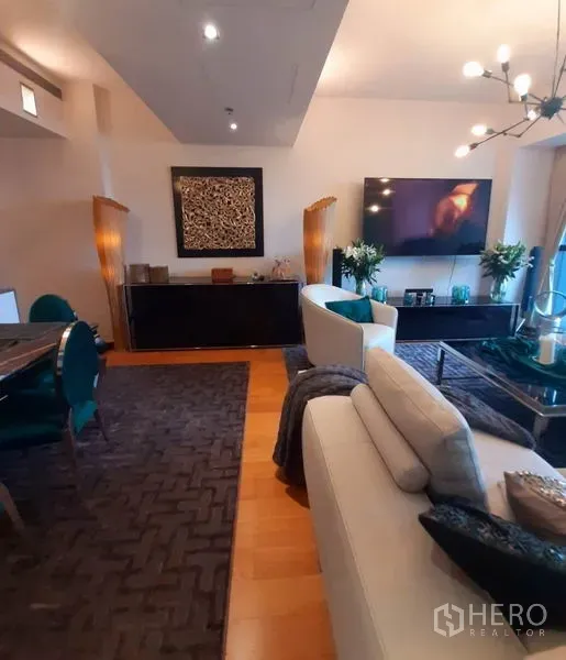 Condominium for rent or sale in Sathon, Bangkok - View of the living and dining space with a large TV console, textured rugs and contemporary lighting.