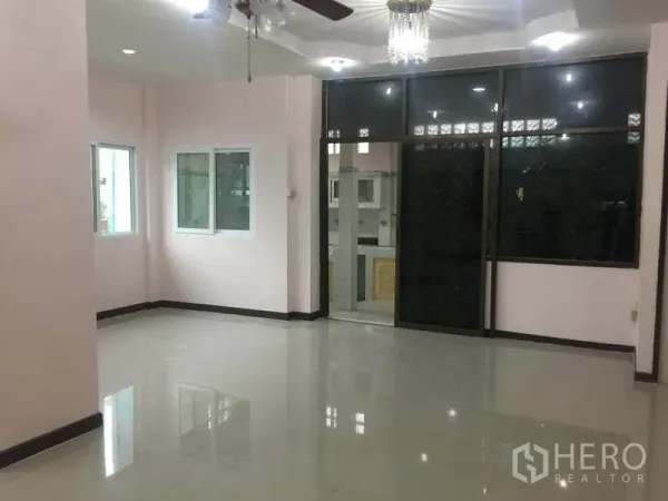 บ้าน ให้เช่าในChatuchak, Bangkok - ห้องนั่งเล่นกว้างพื้นกระเบื้องมันวาว มีพัดลมเพดานและผนังกระจกกั้นครัว