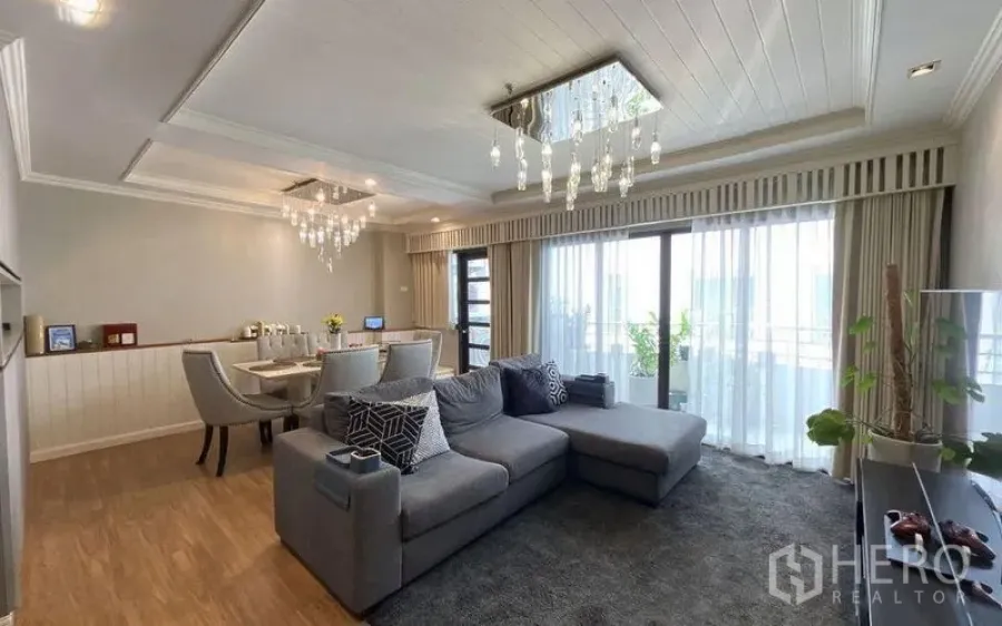 Condominium for sale in Watthana, Bangkok - Open-plan living and dining area with chandeliers and wide windows to the balcony.
