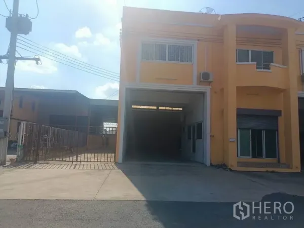 คลังสินค้า ให้เช่าในPathum Thani - ด้านหน้าโกดังสีเหลือง ติดถนน ประตูม้วนกว้าง พร้อมทางเข้ารั้วและลานจอด.