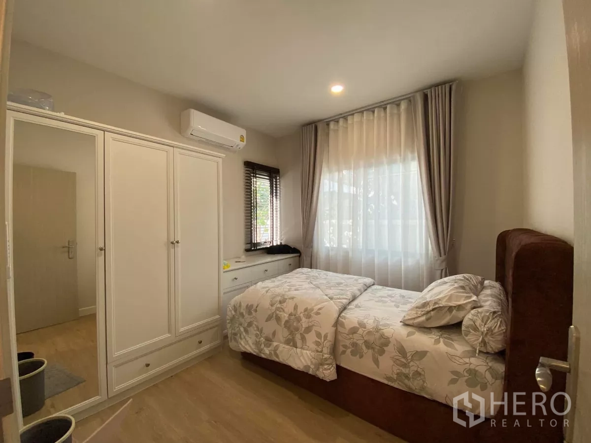 Detached House for rent in Bang Phli, Samut Prakan - Cozy bedroom with floral bedding, white wardrobe and large curtained window.