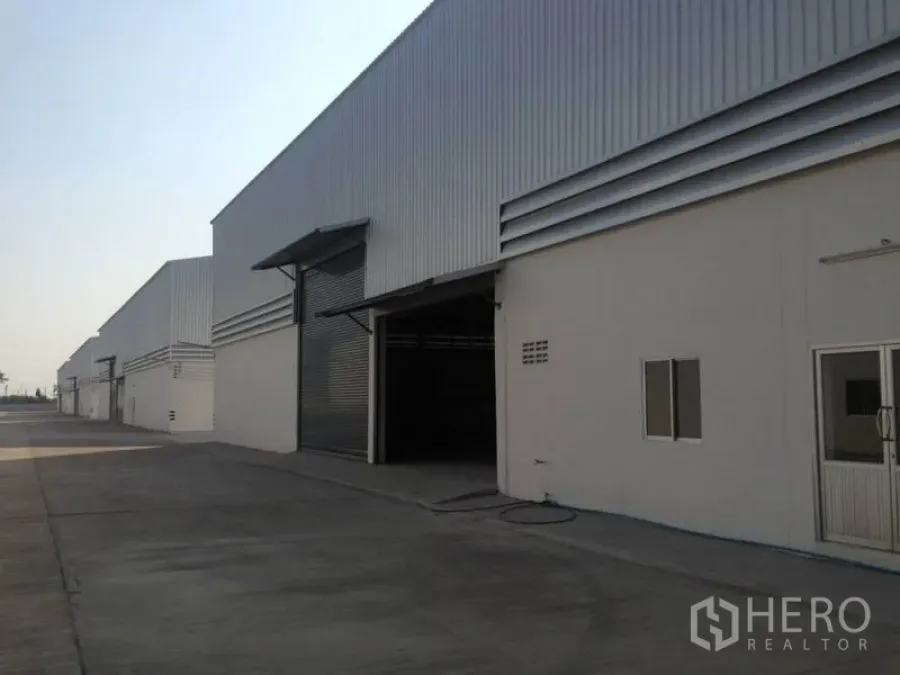 Warehouse for rent in Bang Bua Thong, Nonthaburi - Row of steel‑clad warehouses with large loading doors and canopies in Nonthaburi.