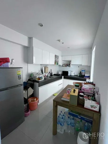 คอนโด ขายในBangkok - ครัวรูปตัวแอลโทนสีขาวพร้อมเครื่องใช้ ชั้นวาง และหน้าต่าง