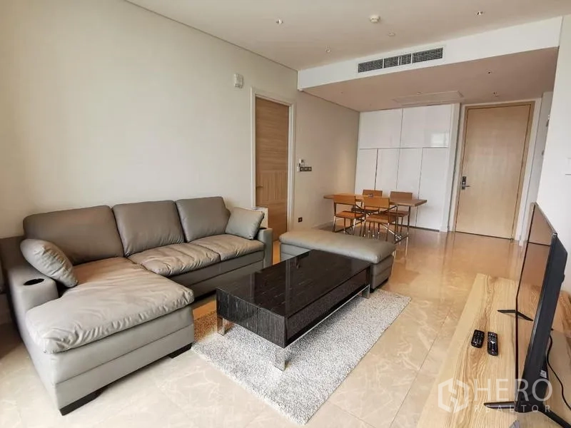 Condominium for rent in Pathum Wan, Bangkok - Open-plan living and dining space with sofa, dining table and entry storage.