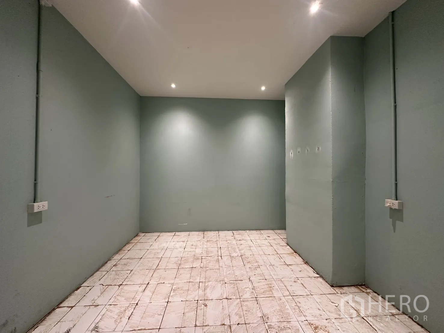 พื้นที่ขายของ for rent in Watthana, Bangkok - ห้องแคบผนังสีเขียว พื้นกระเบื้อง ไฟสปอตบนฝ้า และปลั๊กไฟตามผนัง