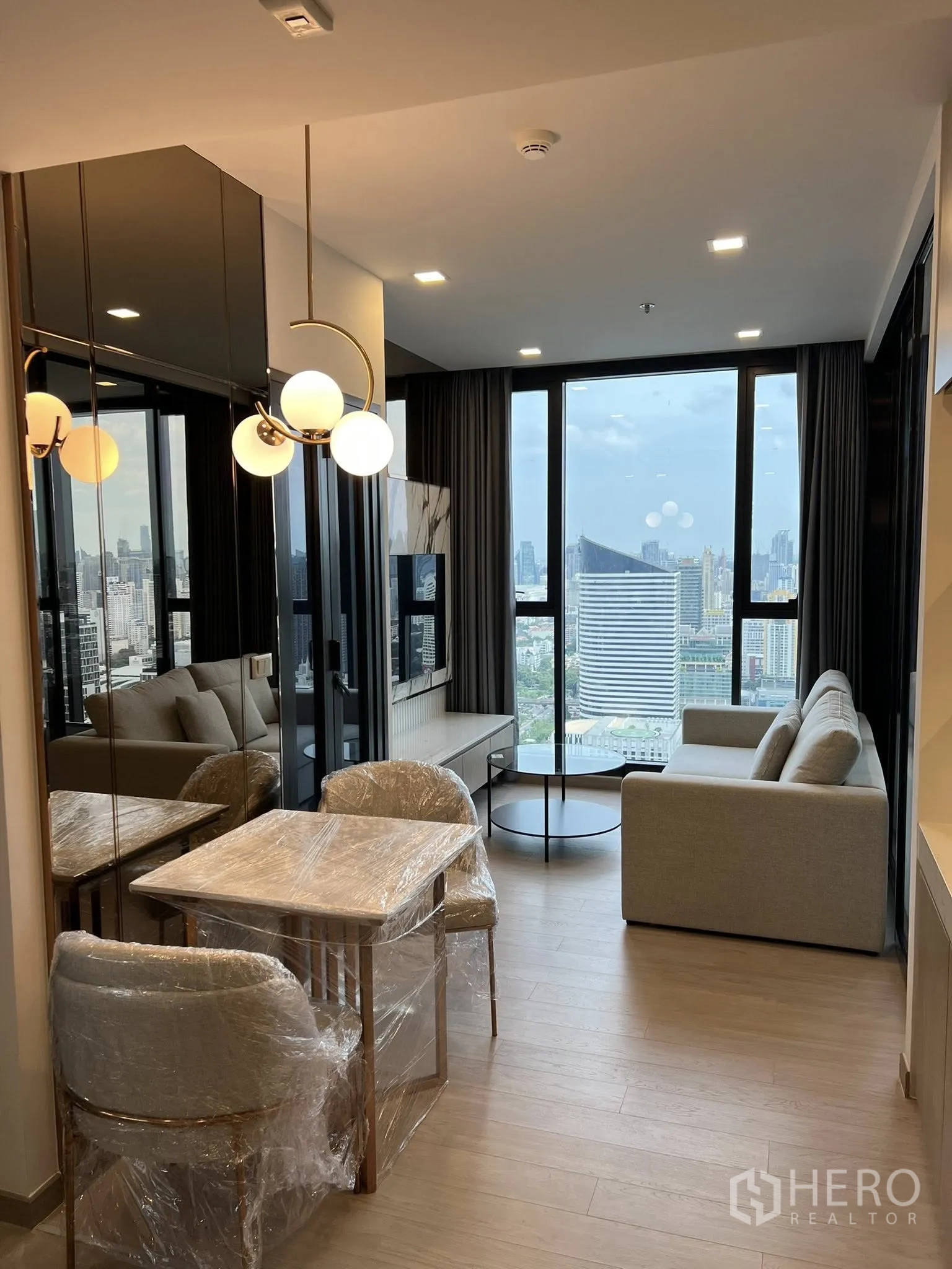 公寓 for rent in Huai Khwang, Bangkok - 餐桌与客厅面向大窗，圆形茶几与现代大理石电视墙。