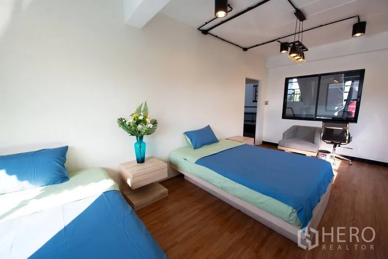 带办公室的家 出租或出售在Phra Khanong, Bangkok - 卧室含一张大床与一张单人床，办公椅与现代吊灯。