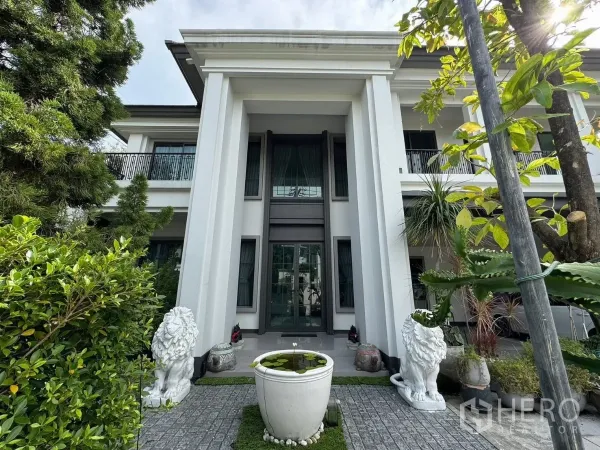 独立式住宅 出售在Mueang Pathum Thani, Pathum Thani - 宏伟门庭，高柱与玻璃门，两侧狮子雕像与庭院水缸。
