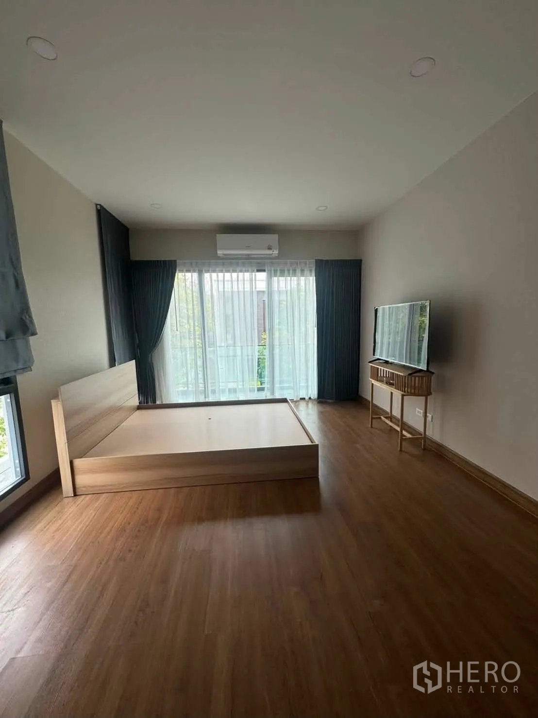 บ้านเดี่ยว for rent or sale in Prawet, Bangkok - ห้องนอนกว้างมีเตียง ทีวีบนชั้นวาง ประตูกระจกสูงพร้อมผ้าม่าน และแอร์