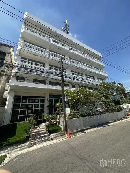 Home Office for rent in Phra Khanong, Bangkok - White multi‑storey building exterior with balconies and a glass-fronted ground level.