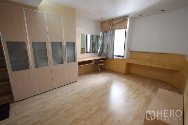 公寓 出租在Watthana, Bangkok - 宽敞卧室，整墙衣柜、书桌以及带窗帘的大窗户。