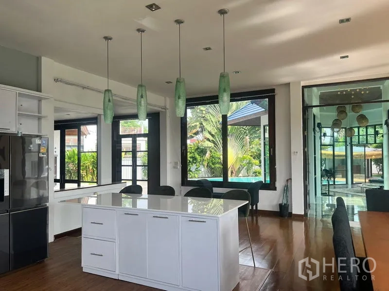 Detached House for sale in Prawet, Bangkok - Kitchen and living space with large windows and island facing the pool area.