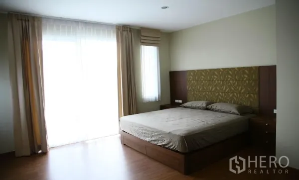 Detached House for rent or sale in Bang Na, Bangkok - Spacious master bedroom with upholstered headboard, king bed, wood flooring and floor-to-ceiling windows.