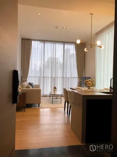 Condominium for rent - Entry view to a bright living area with kitchen island, chandelier and floor-to-ceiling curtains.