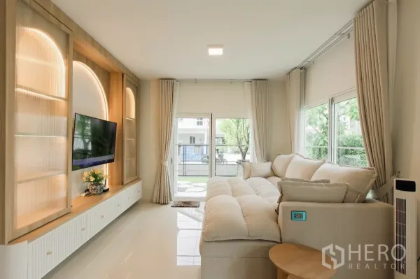 独立式住宅 出租或出售在Bang Phli, Samut Prakan - 客厅设有内置电视墙、暖色灯带与两侧窗户。