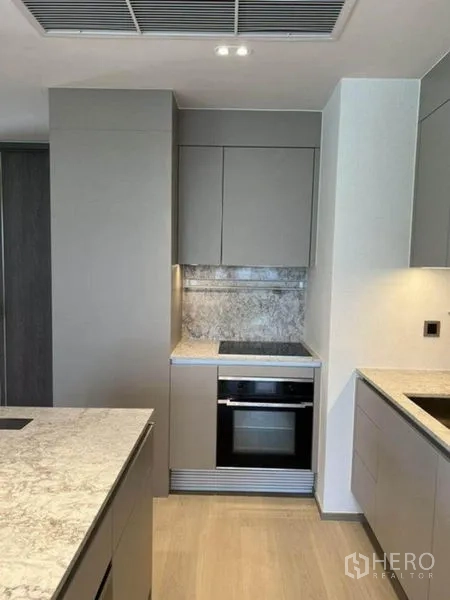Condominium for rent in Pathum Wan, Bangkok - Sleek built-in kitchen with oven and stone backsplash lighting.