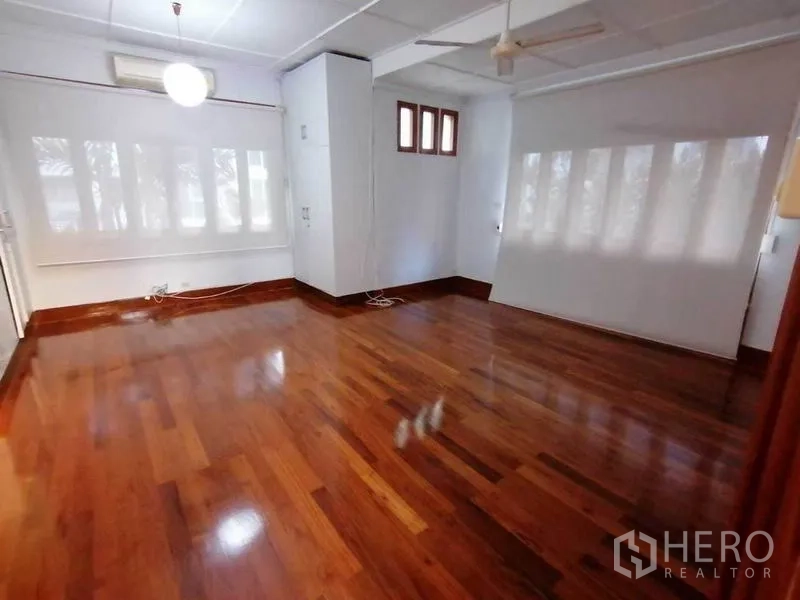 Detached House for rent in Pathum Wan, Bangkok - Spacious room with glossy hardwood floors, roller blinds and a ceiling fan.