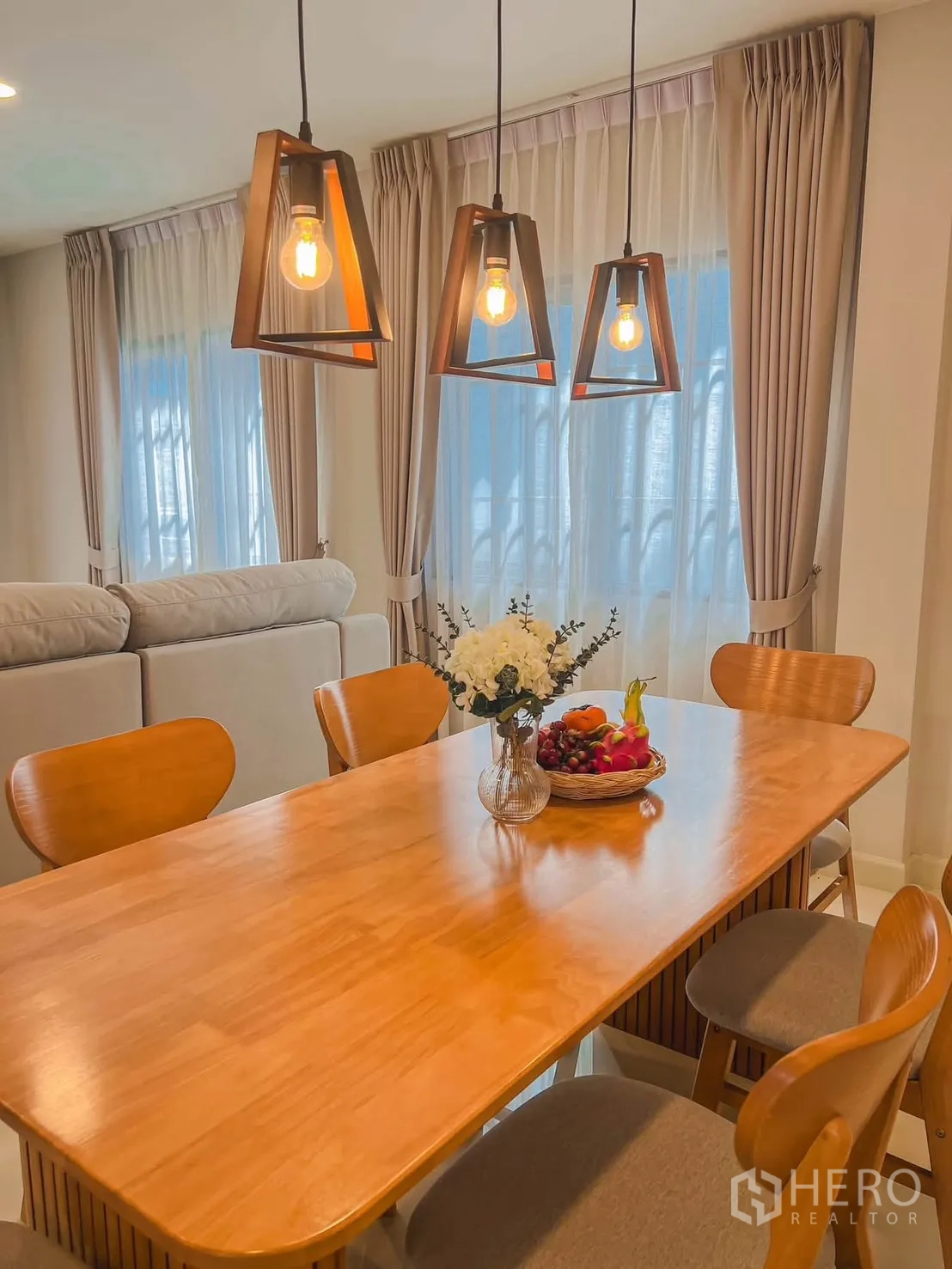 独栋房屋 for rent in Bang Phli, Samut Prakan - 餐区木质餐桌六椅，三盏吊灯与落地窗帘。