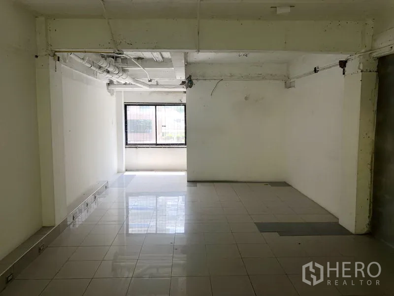 零售空间 出租在Khlong Toei, Bangkok - 开放式零售空间，白色墙面、瓷砖地面、外露管线与明亮采光窗。