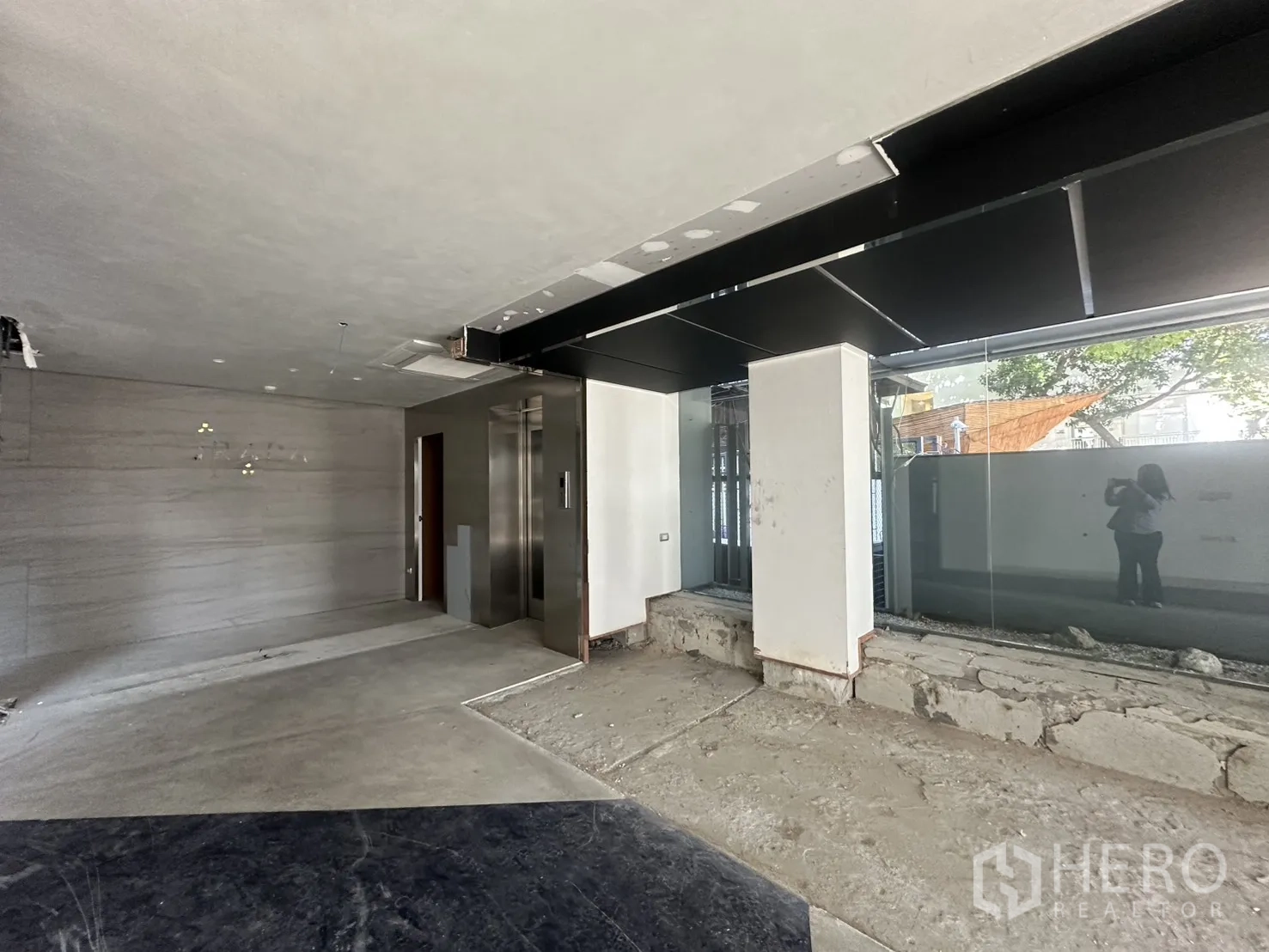 Retail Space for rent in Watthana, Bangkok - Open-plan area with a glass storefront and a visible elevator lobby to the rear.