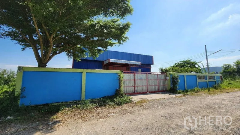 货栈 出租在Nong Chok, Bangkok - 临街大门与实体围墙，门外有大树遮荫。