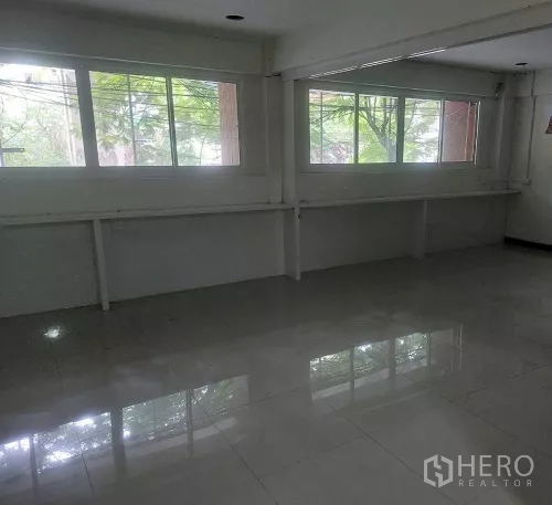 Shophouse for rent in Bang Rak, Bangkok - Upper floor workspace with long windows overlooking leafy street trees.