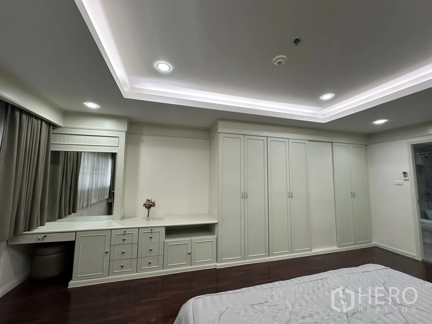 Condominium for rent in Watthana, Bangkok - Bedroom with built-in wardrobes, dressing desk, and wood flooring.