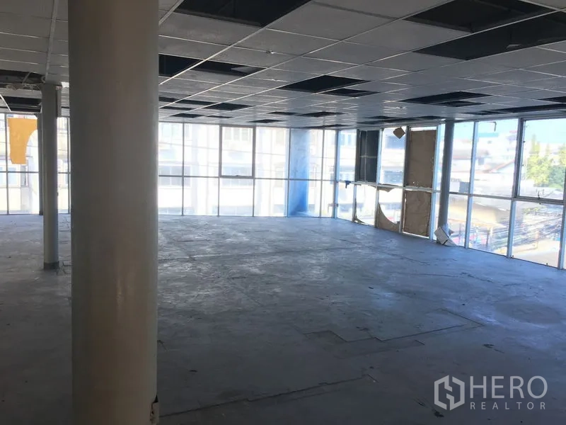 Warehouse for rent in Suan Luang, Bangkok - Spacious corner office floor with floor-to-ceiling windows and tiled ceiling panels providing natural light.