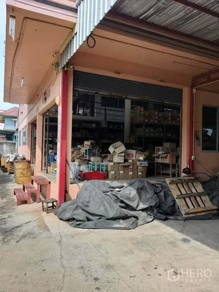 零售空间 出售在Bang Khun Thian, Bangkok - 一层仓储门面，卷帘门开启，可见内部货物。