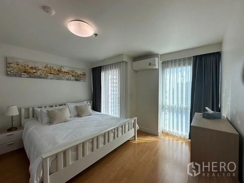 公寓 出售在Bang Rak, Bangkok - 转角卧室，白色床架，双面窗户与窗纱，配空调。