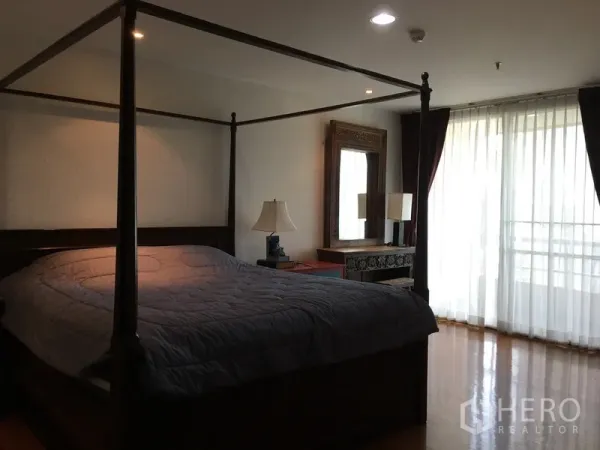 Condominium for rent in Pathum Wan, Bangkok - Spacious master bedroom with four-poster bed and floor-to-ceiling sheer curtains leading to a balcony.
