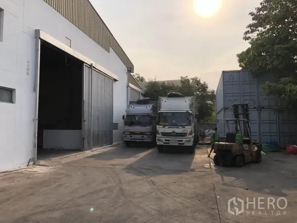 工厂 出租在Bang Bua Thong, Nonthaburi - 厂房侧装卸场，集装箱卡车与叉车通道，夕阳光线。