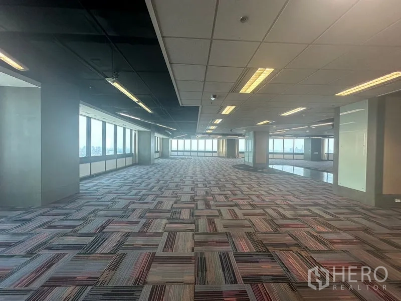 Office Space for rent in Khlong Toei, Bangkok - Long open-plan office with rows of lights and large windows.