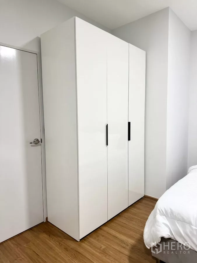 Townhouse for rent in Bang Phli, Samut Prakan - Bedroom wardrobe with three white doors on wood flooring.