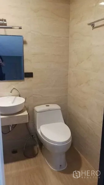 Townhouse for rent in Khlong Toei, Bangkok - Compact bathroom with vessel sink, toilet and light beige wall tiles.
